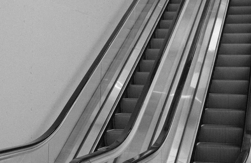 A pair of escalators ascending side by side inside a building